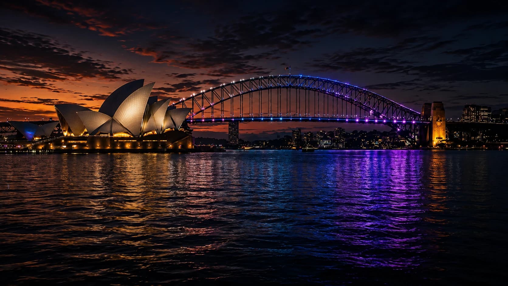 Sydney Opera House and Harbour Bridge lit up at sunset